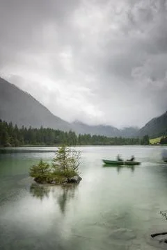 Vertical shot of a fishing boat in a lake with a background forests Stock Photos