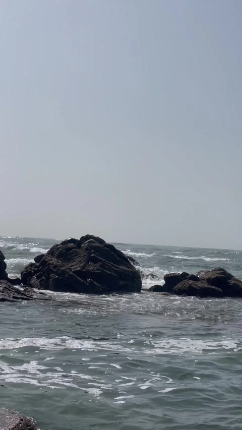 Vertical Shot of Foamy Waves Breaking Over Large Coastal Boulders Stock Footage 340775087