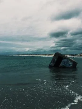 A vertical shot of a gray square object floating on the body of water under a Foto stock