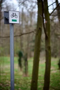 Vertical shot of a green cycle path navigation sign on a metal post in a fore 库存照片