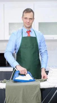 Vertical shot. handsome man in tie and apron stroking linen Stock Illustration