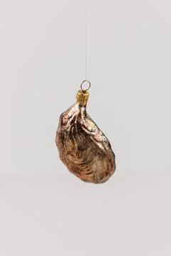 Vertical shot of a hanging bauble in the shape of an oyster shell on a white bac Stock Photos