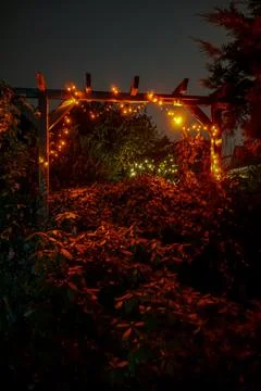 Vertical shot of hanging illuminated string lights on a wooden fence outdoors Stock Photos
