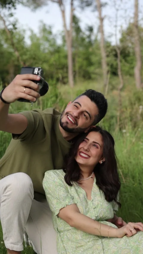 Vertical shot of a happy couple taking a selfie with camera at a picnic Stock Footage 288855797