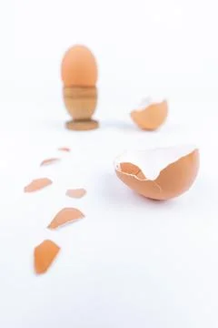 Vertical shot hen egg in old wooden egg stand and multiple broken egg shells on Stock Photos