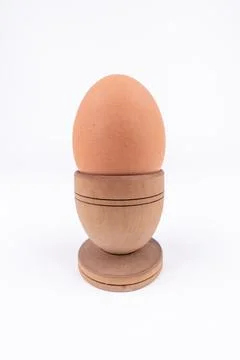 Vertical shot of hen egg in old wooden egg stand isolated on white background Stock Photos
