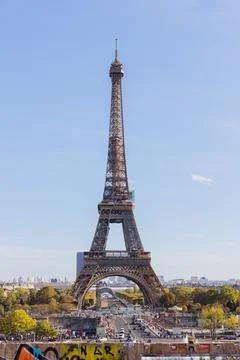 Vertical shot of the historic Eiffel Tower with a crowd of people nearby in Pari Fotos de archivo