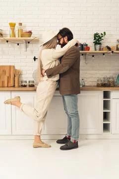 Vertical shot of a hug between two caucasian lovers, woman lifting her one leg Stock Photos