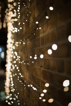 Vertical shot of illuminated string lights covering the wall of a building at Stock Photos
