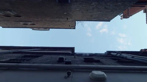 Vertical shot looking up through buildings towards blue sky Stock Footage 148622535
