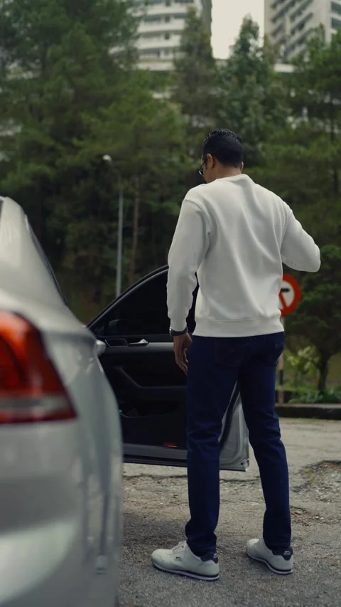 Vertical shot of a man getting into a parked car in Genting Highlands Stock Footage 328402220