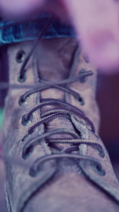 Vertical shot of man in jeans tying the laces of his old work boots, with sound Stock Footage 227923901