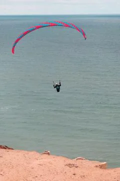 Vertical shot of a man practicing the paragliding over over the North Sea coast Fotos Stock