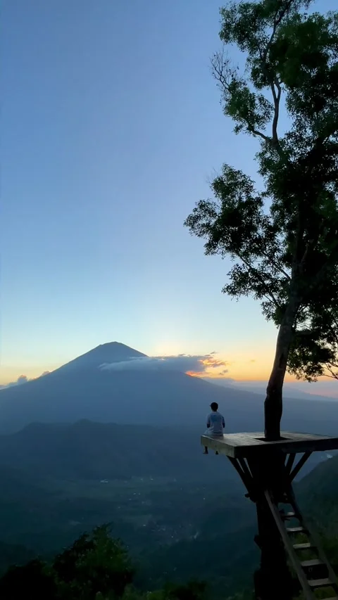 Vertical Shot of Man Sitting on Tree Deck Watching Mount Agung Sunset Video stock 341719396