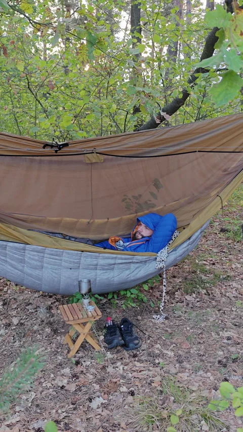Vertical Shot of Man Sleeping in Hammock during Autumn Wild Camping Stockbeeldmateriaal 346549760