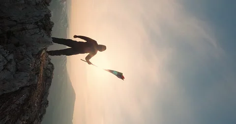 Vertical shot of a man standing with rainbow LGBT flag at the mountain peak Stock Footage 248176221