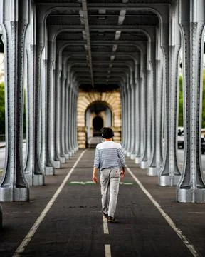 Vertical shot of a man walking in the Bridge of Bir-Hakeim in Paris 写真素材
