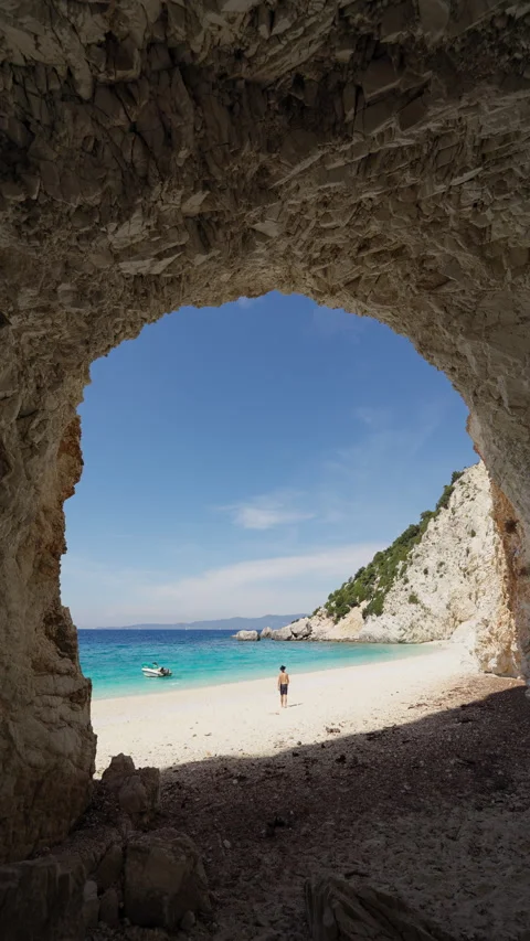 Vertical shot of man walking through rocky cave at Platinamos Beach, Ithaca 動画素材 309095941