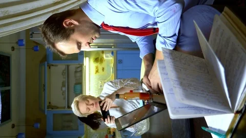 Vertical shot. a man working at home on the laptop in the kitchen, wife eats Stock Footage 127481782