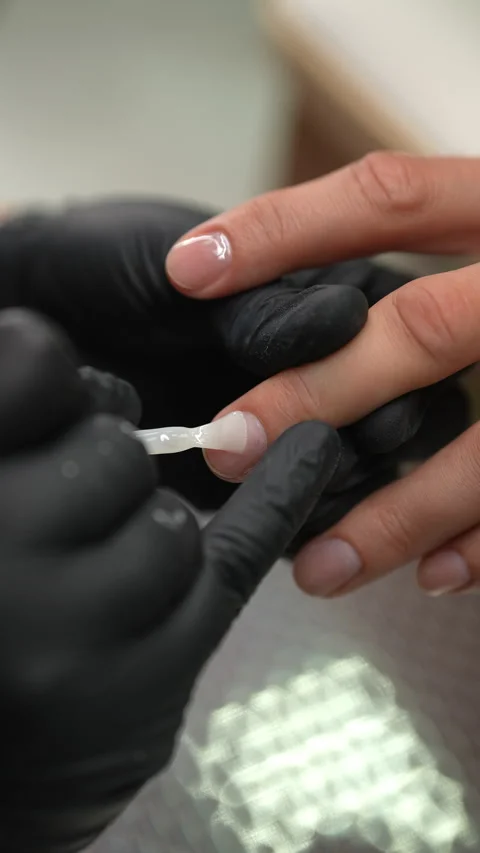 Vertical shot of manicurist skillfully applying layer of reinforcing clear nail Stock Footage 284381449