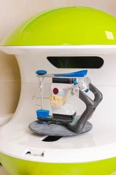 Vertical shot of a modern 3d printer at a dentistry with dental prothesis. Stock Photos