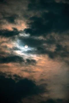 Vertical shot of the Moon against a dramatic cloudy sky at night perfect for wal Stock Photos