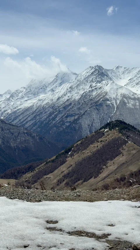 Vertical shot of mountain peaks rising above a broad valley within an open Stock Footage 335940108