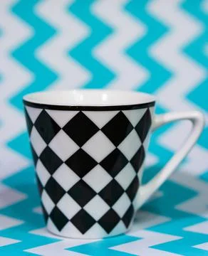 Vertical shot of a mug with a chess tile pattern on a zigzag backgroun Stock Photos