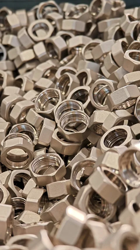 Vertical shot of multiple steel nuts piled up. Industrial manufacturing and Stock Footage 329311170