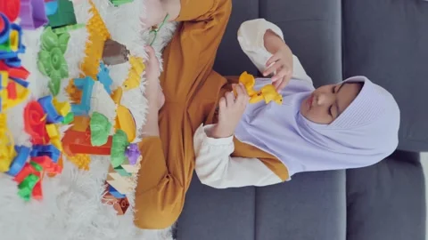 A vertical shot of a Muslim girl is playing with toys alone in the living room. Stock Footage 143785553
