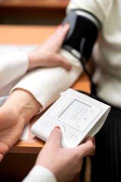 Vertical shot of a nurse's hand checking a patient's blood pressure in a Stock Photos