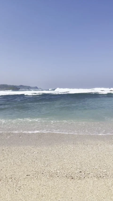 Vertical shot of ocean waves breaking on a tropical sandy beach Stock Footage 338370525