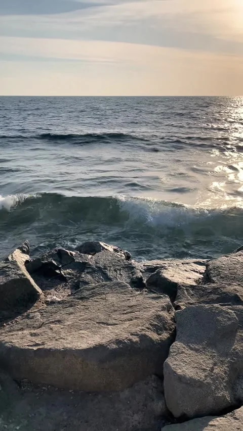 Vertical shot of ocean waves crashing against a rugged rocky breakwater 스톡 동영상 342871092