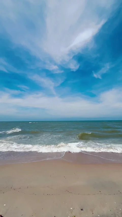 Vertical shot of ocean waves washing on a sandy beach Stock Footage 336400329