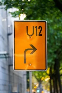Vertical shot of orange rectangular U12 road sign with arrow Stock Photos