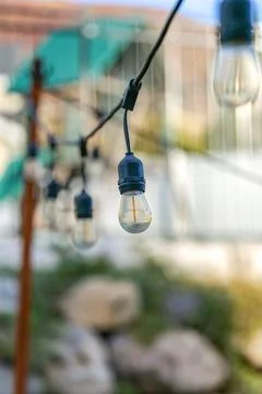 Vertical shot of of outdoor decorative string lights in a garden Stock Photos
