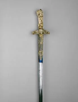 Vertical shot of a pattern sword with a golden handle on white background Foto stock