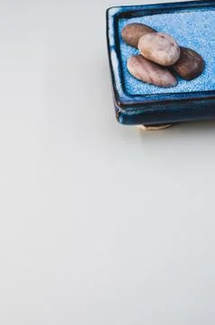 A vertical shot of pebbles on a rectangular box filled with small blue rocks  Stock Photos