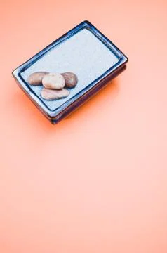 A vertical shot of pebbles on a rectangular box filled with small blue rocks  Foto stock