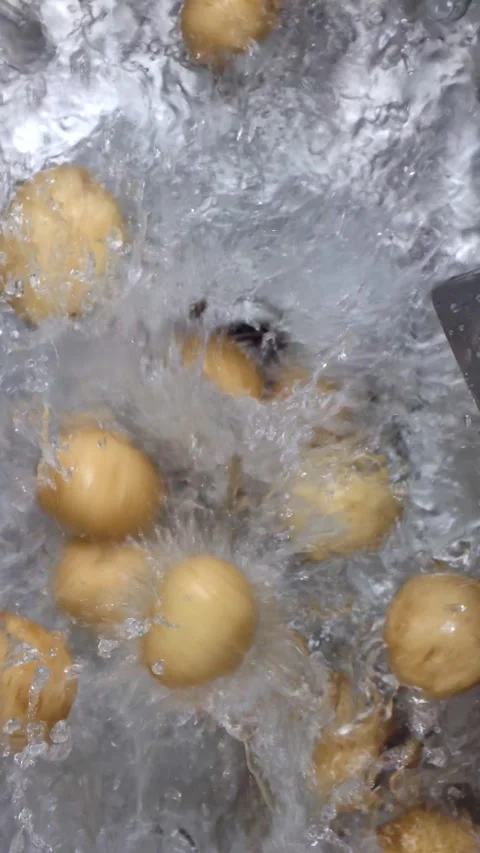 Vertical shot: piles of potatoes fall into the water Stock Footage 344833051