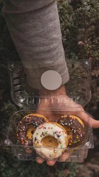 Vertical shot of a plastic pack of donuts in a human hand Stock Photos