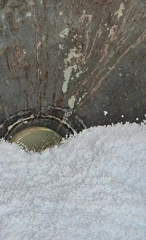 Vertical shot of polystyrene beads pouring into vacuum suction hose Stock Footage 340276238
