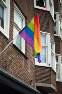 Vertical shot of the pride flag hanging from a wall 스톡 사진