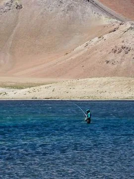 Vertical shot of a professional angler casting for trout in a high-altitude.. Stock Photos