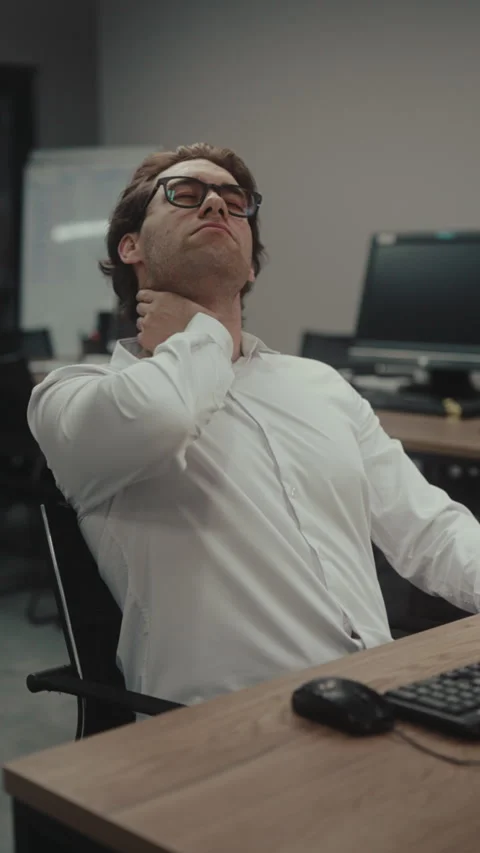 Vertical shot of programmer sitting at computer office feels tired and has neck 動画素材 342931582