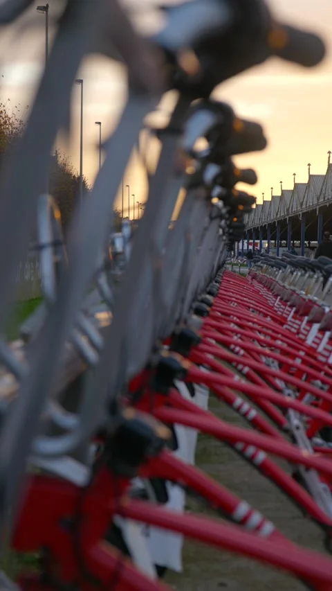 Vertical shot of rack of red sharing bikes in city at golden hour Video stock 222071272