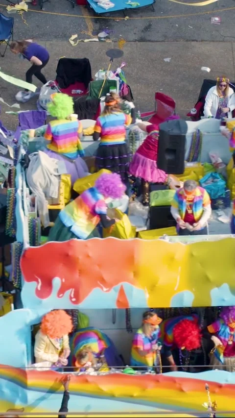 Vertical shot of a rainbow-themed parade float as riders sort and toss colorful Stock Footage 323188503