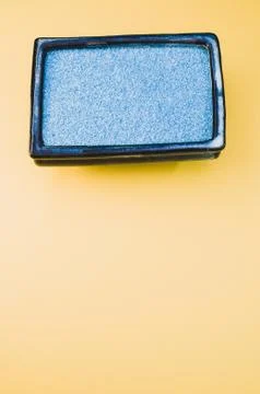 A vertical shot of a rectangular box filled with small blue rocks on yellow b 스톡 사진