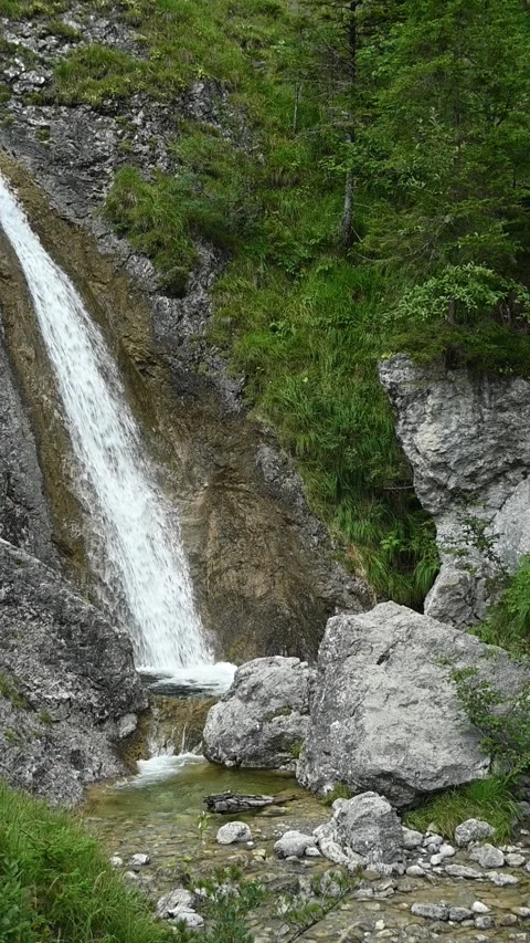 Vertical shot of rocks, a waterfall and a mountain stream, slow motion Video stock 260891326