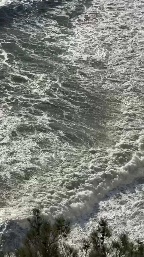 A vertical shot of rocky cliffs rising above the sea surface. A calm view of the Stock Footage 275476161